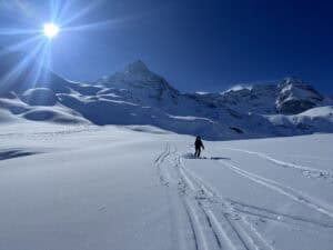 Skier freeriding on fresh snow in the Arlberg region under clear blue sky.