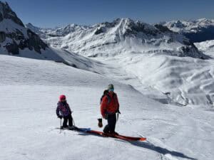 Skier and child enjoying freeriding on snowy slopes in Arlberg mountains.